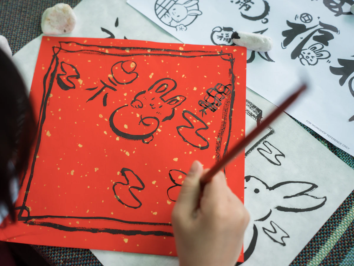 A child painting on red paper with a calligraphy brush
