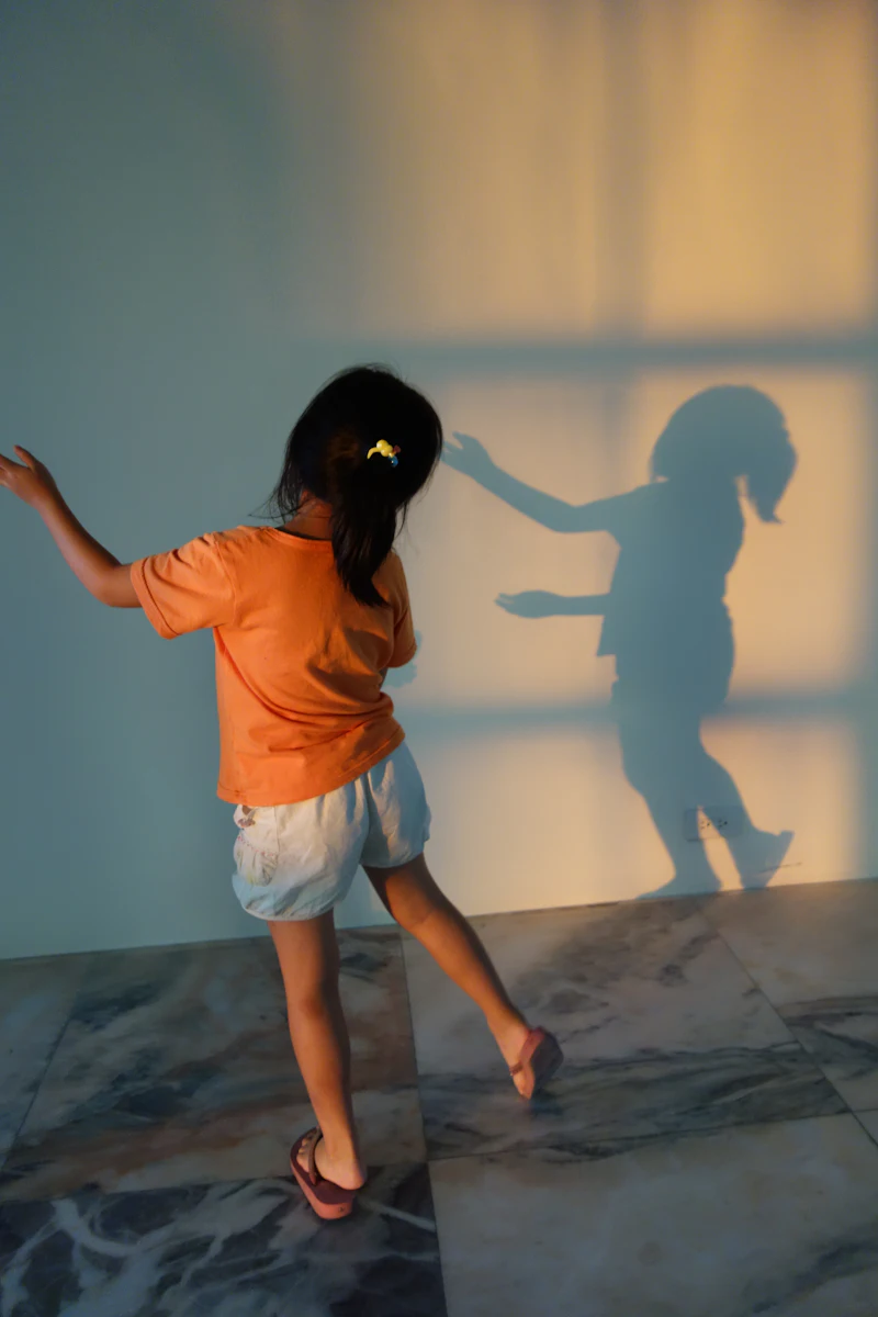 A young girl dancing beside her shadow