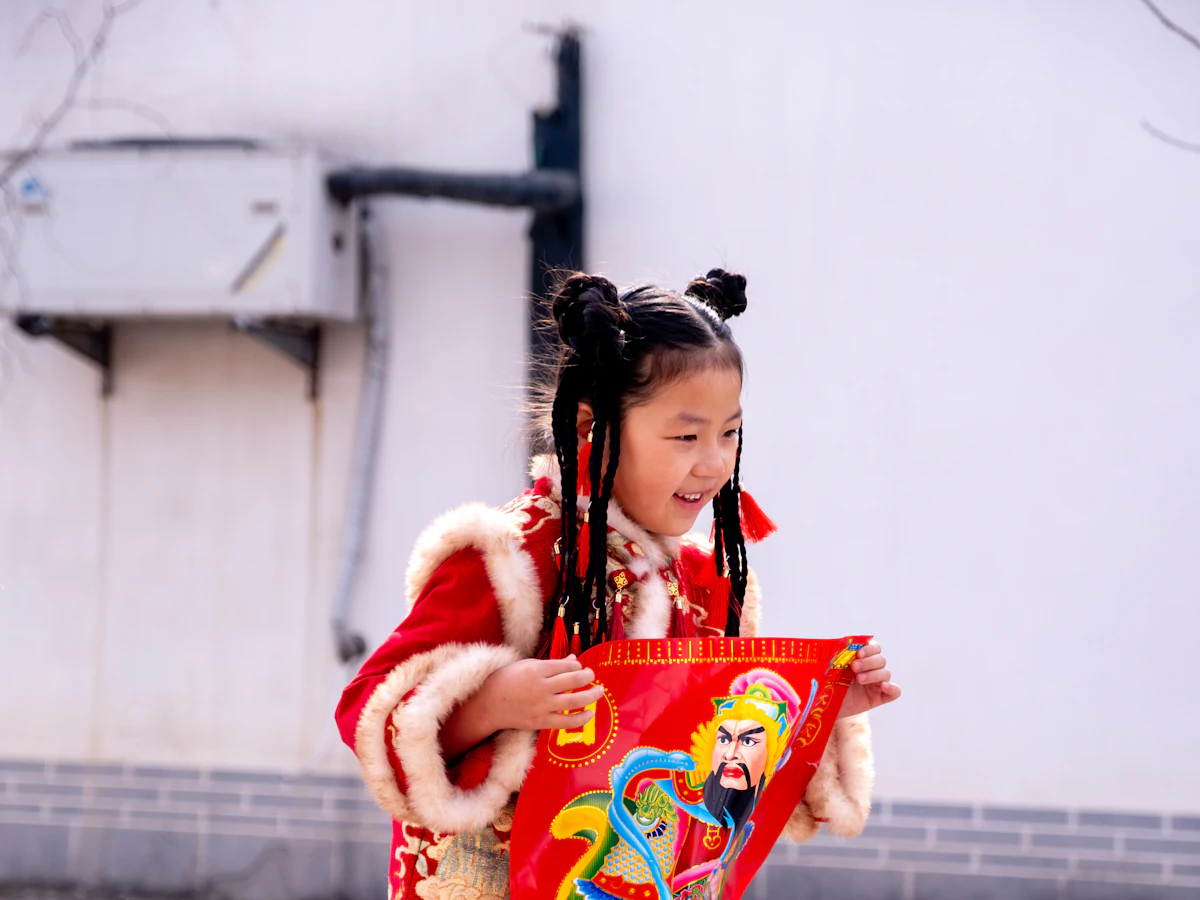 A girl in a red festival jacket holding a New Year picture