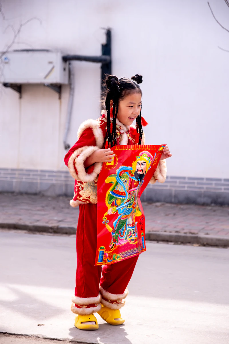 A girl in a red festival jacket holding a New Year picture