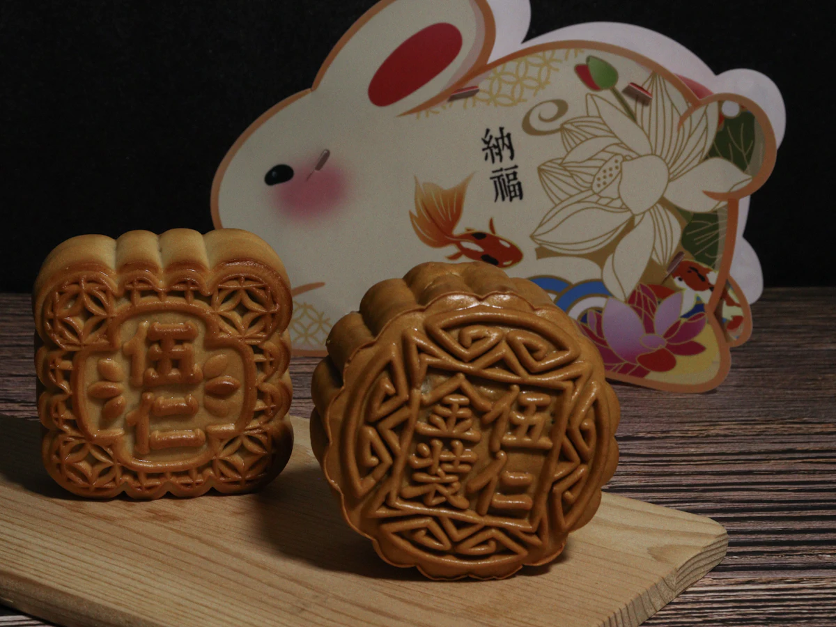 Two mooncakes on a board beside a paper rabbit