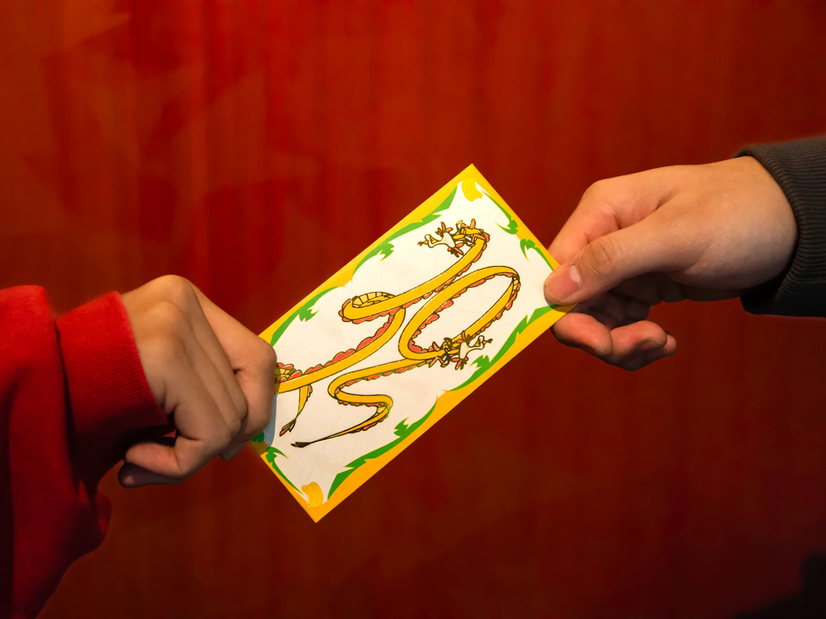 One person handing another a red and gold envelope