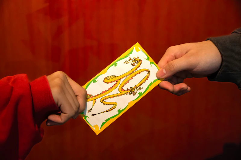 Hands passing a red and gold envelope