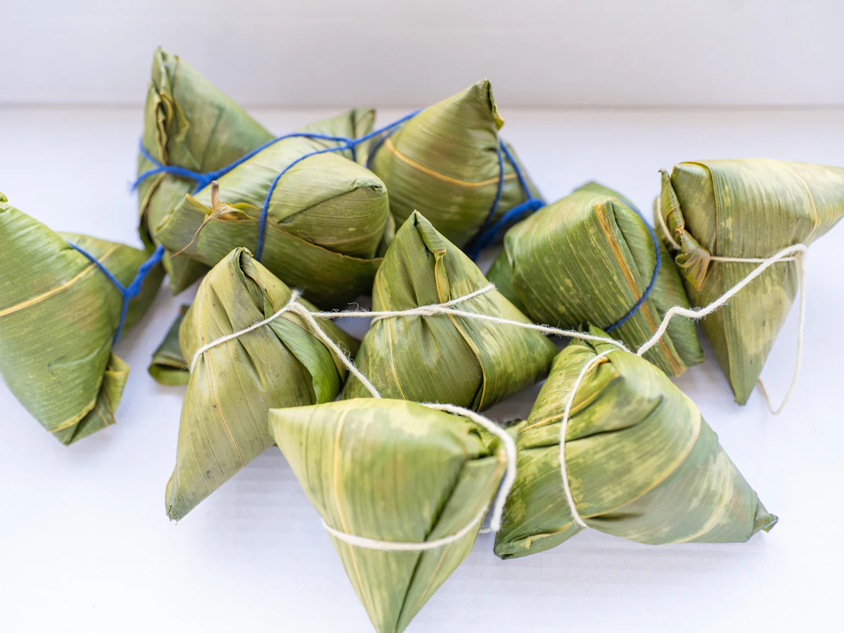 A pile of zongzi, sticky rice parcels wrapped in green leaves and tied with string